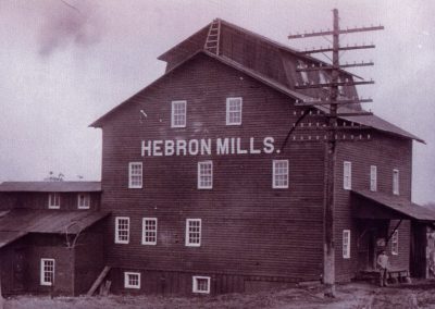 The Hebron Mills building outside with two men sepia tone